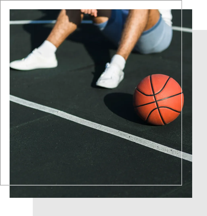 A person sitting on the ground next to a basketball.