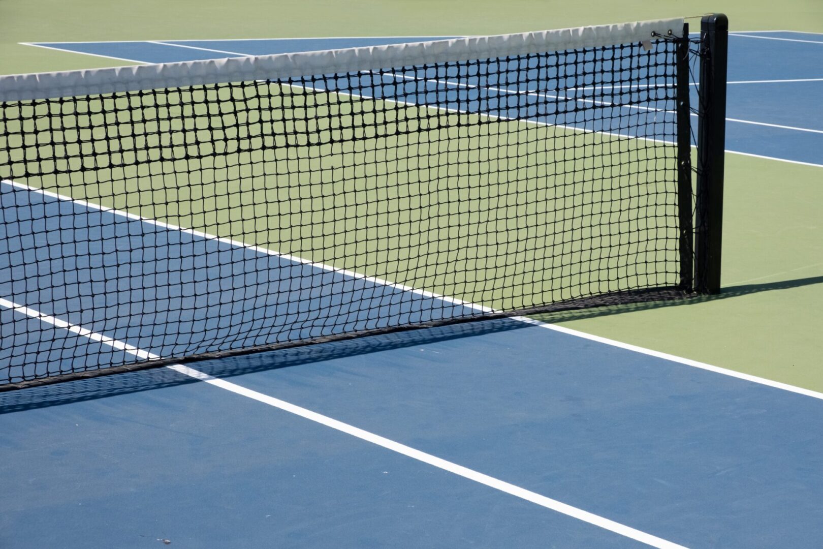A tennis court with a net and the blue line.